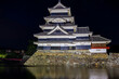 Ancient Japanese Matsumoto Castle at night with a reflection in the moat