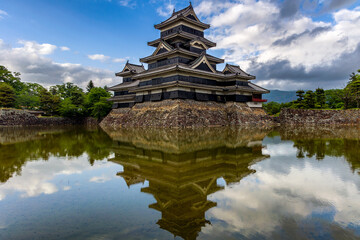 Canvas Print - Ancient Japanese castle reflected in its moat with a blue sky behind (Matsumoto)