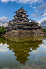 Canvas Print - Ancient Japanese castle reflected in its moat with a blue sky behind (Matsumoto)