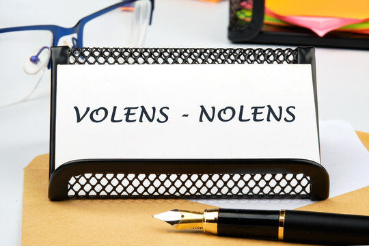 Willy - nilly latin expression volens-nolens (willing or unwilling) written on a business card on the table