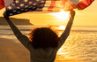 African American Girl Teenager Holding an American US Flag on a Beach at Sunset