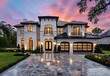 New luxury home exterior at dusk with a large driveway and garage, 