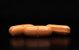 Fototapeta  - close up of three pills on a black background