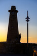 A man standing and smoking by the lighthouse of Kyrenia Harbour at the blue hour in Cyprus