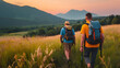 Two men with hiking backpacks travel in mountains at sunset. group of tourists goes hiking in nature in warm summer weather. Friends, beautiful landscape, orange and yellow colors