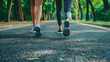 Forward Together on the Path. A close-up of a young couple's feet in motion, showcasing the rhythm of their walk or run on a leaf-strewn park path, signaling health and partnership.