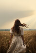 Historical representation of a pretty young pioneer mennonite woman with long brown hair and white dress. Back view. Vibrant cinematic field background. Old west, wild west. Hair blowing in wind