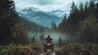 Person riding an ATV on forest trail facing snow-capped mountains and mist