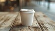 A sleek white paper cup sits on a plain light wood.