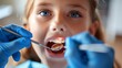 A child's open-mouthed curiosity during a dental checkup, contrasted by the precise movements of blue-gloved hands tending to oral health. A timeless dental moment.
