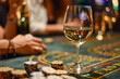 A casino table with a glass of wine, people playing their chips