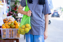 Teen Girl Carry Net Tole Bag Of Oranges,standing At Community Fruits Store, Female Teenager Using Environmentally Friendly Bags For Support To Stop Global Warming