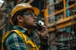 A construction worker talking to a walkie talkie / portable communication device 