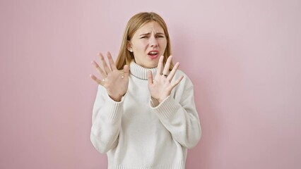 Poster - Terrified blonde girl yells in panic, fear evident in expression, hands raised as stop gesture - beautiful isolated over pink background