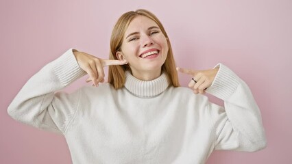 Canvas Print - Cheerful blonde girl pointing at perfect dental health with a big smile, standing over pink isolated background