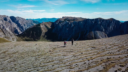 Wall Mural - Aerial view of hiker couple on idyllic hiking trail on alpine meadow in majestic Hochschwab mountain range, Styria, Austria. Wanderlust in remote Austrian Alps. Sense of escapism, peace, reflection