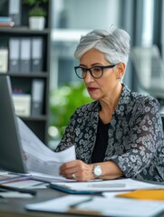 Mature female entrepreneur brainstorming while reading an e-mail on a computer in the office