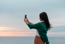 Smiling Woman Taking Selfies During Peaceful Sea Sunset