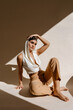 © Tania Cervian/Stocksy - Stylish woman sitting on floor in shadow cut light while touching head