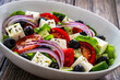 Greek style salad - fresh vegetables with feta cheese on wooden table
