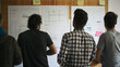 A man is attaching a wireframe sketch to a board covered in design materials.