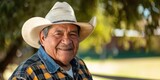 Fototapeta Uliczki - Smiling senior hispanic man wearing a cowboy hat looking at the camera	