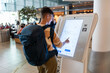 © Alvaro Lavin/Stocksy - Traveler using touch screen at airport.