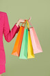 © Marc Tran/Stocksy - Hand holding paper shopping bag colorful four on green background