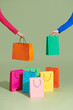 © Marc Tran/Stocksy - Shopping bag logo. Hand holding a shopping bag on green background