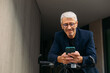 © Studio Firma/Stocksy - Senior man using mobile phone outside