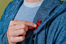 Man Pinning A Red Ribbon In His Lapel
