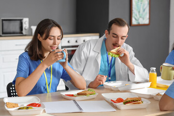 Sticker - Female doctor having lunch with her colleagues at table in hospital kitchen