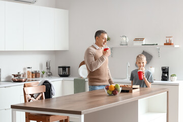 Wall Mural - Mature doctor with his little son drinking soda in kitchen