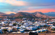 Landscape aerial view of the Municipality of Yaiza village illuminated by the sunset at the foot of the volcanic mountain, in Lanzarote - Canary Islands, Spain