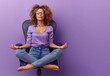 middle age woman meditating on an office chair isolated over purple color background