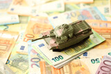 Fototapeta Młodzieżowe - Many euro banknotes and tank. Lot of bills of European union currency and green tank close up