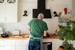 © Alba Vitta/Stocksy - back view of Senior man cooking at home