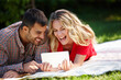 © peopleimages.com - Couple, blanket and tablet to relax on grass, internet and commitment to relationship in outdoor nature. Happy people, bonding and streaming for marriage, romance and online on vacation or holiday