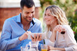 © peopleimages.com - Happy couple, smiling and tablet in garden for breakfast, internet and scrolling on social media. Male person, woman and outdoors at home for mobile games, meme and drinking coffee in the morning.