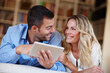 © peopleimages.com - Happy, woman and tablet with husband at house in lounge for weekend away with love, trust and peace as partners. Married, couple and vacation for break, relax and bonding with technology in home.