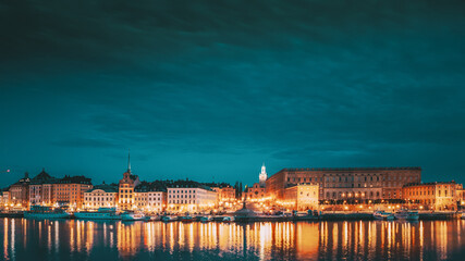 Wall Mural - Stockholm, Sweden. Scenic Famous View Of Embankment In Old Town Of Stockholm In Night Lights. Great Church Or Church Of St. Nicholas And Royal Palace. Famous Popular Destination Scenic Place In Lights