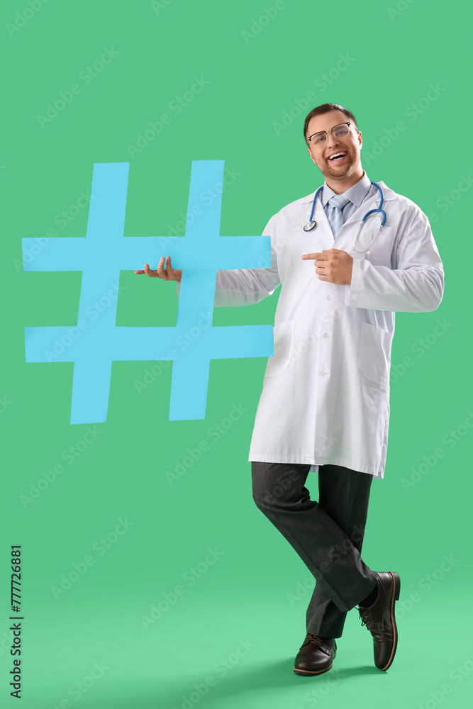 Male doctor pointing at hashtag on green background