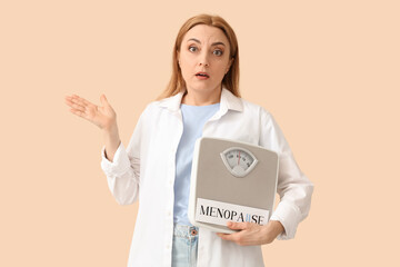 Poster - Mature woman holding paper with word MENOPAUSE and weight scales on beige background