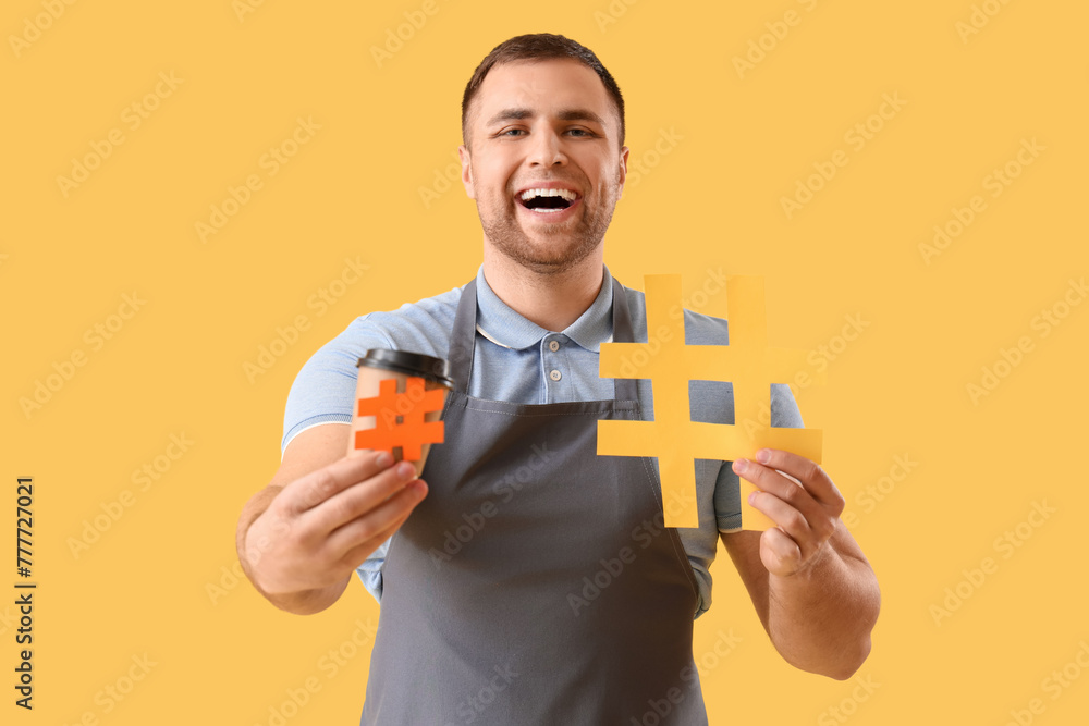 Male barista with hashtags and coffee cup on yellow background