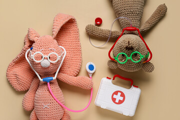 Sticker - Toy first aid kit with teddy bear, toy bunny and stethoscope on beige background. Top view