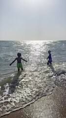 Wall Mural - Happy child playing in the sea. Kid having fun outdoors. Summer vacation and healthy lifestyle concept. two young boys having fun on tropical beach, happy best friends playing