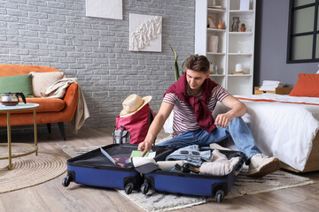 Wall Mural - Male tourist unpacking suitcase in hotel room