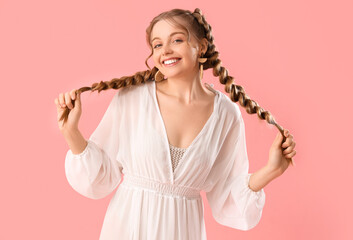 Poster - Happy smiling young woman in dress with braids on pink background