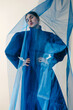 © Tania Cervian/Stocksy - Confident woman wearing blue dress standing behind curtain in studio