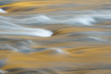  Abstract image of moving water capturing the reflection of light on the surface.